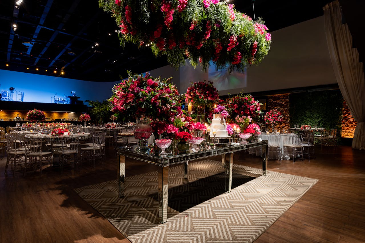 A beautifully decorated wedding venue with vibrant floral arrangements and elegant table settings under romantic lighting.
